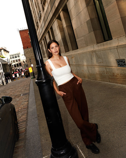 Pantalon brun large et camisole blanche pour femme.